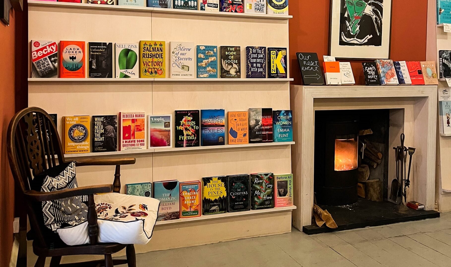 Books on shelves at Golden Hare Books with fireplace and chair to the side.