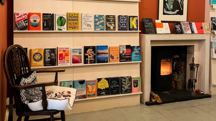 Books on shelves at Golden Hare Books with fireplace and chair to the side.