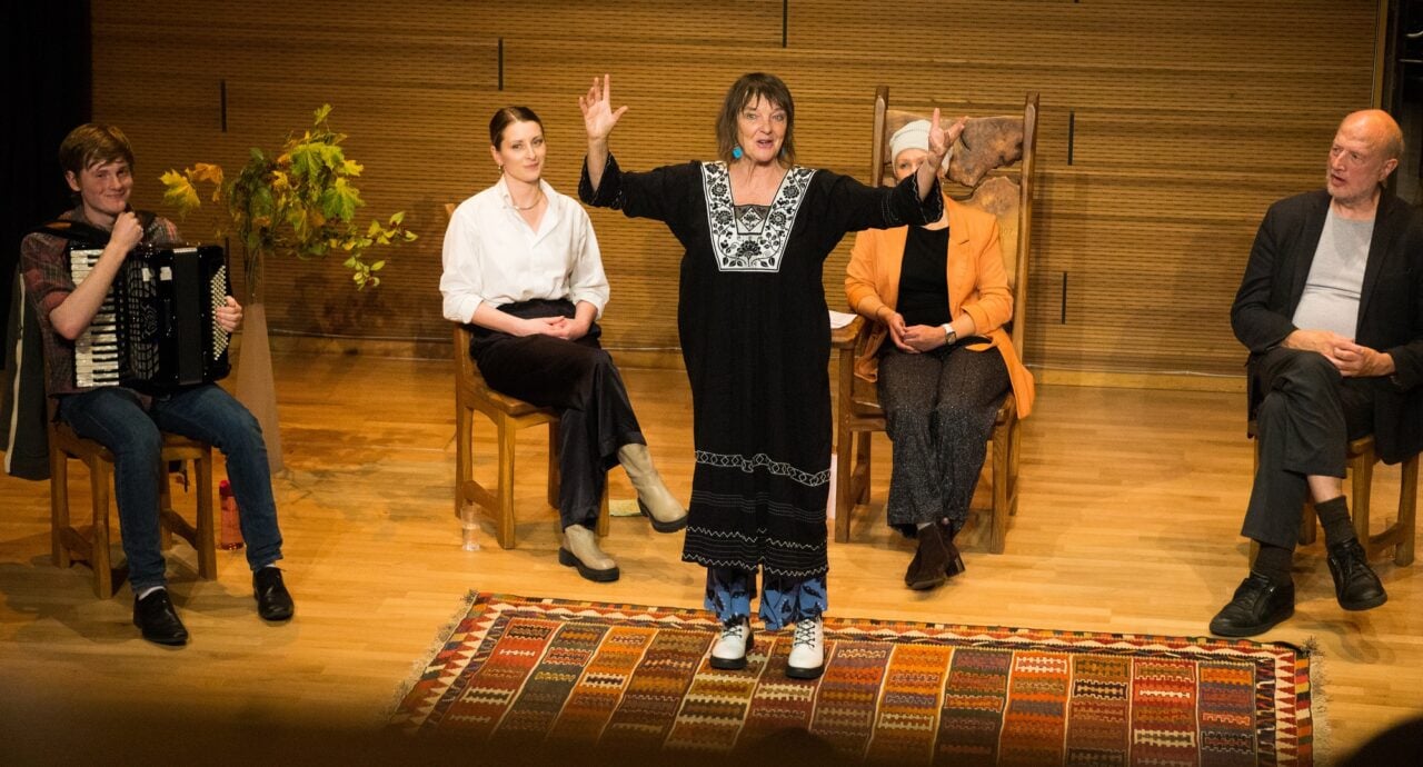 Women standing on stage performing.