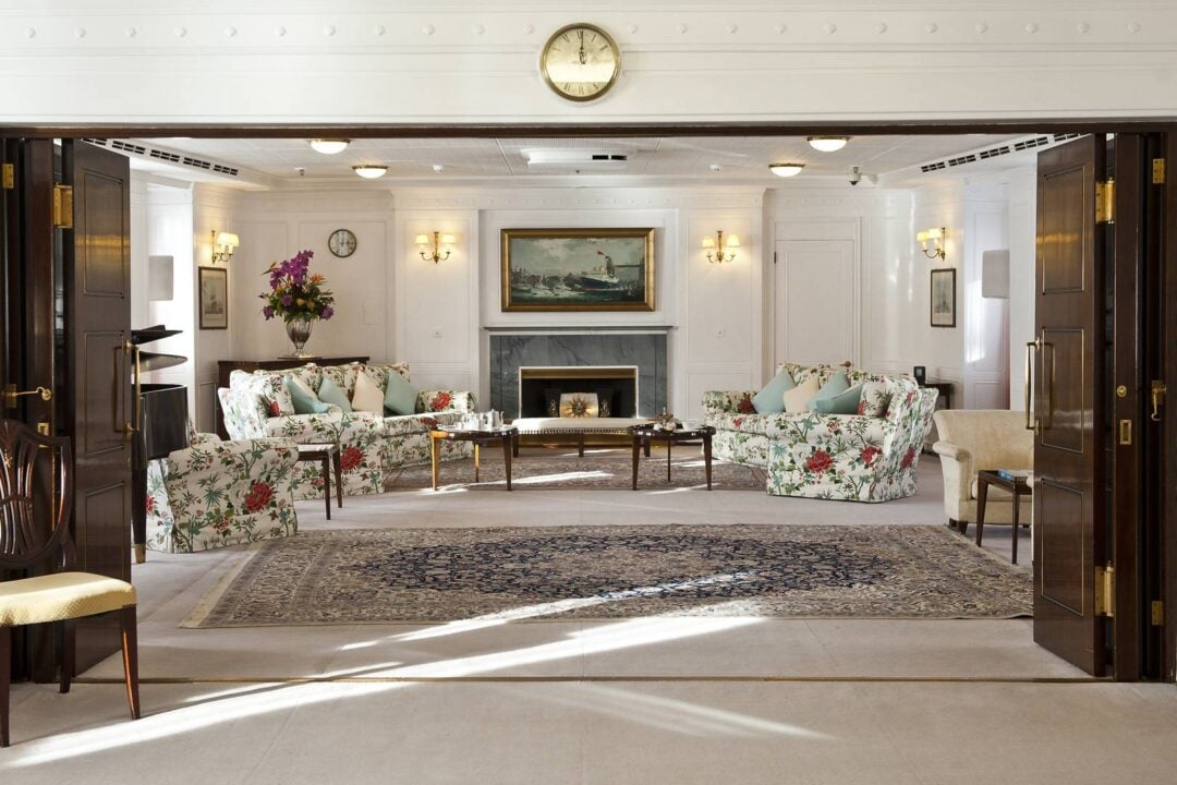 Floral sofas sit either side of the fireplace. A painting of The Royal Yacht Britannia sits above the fireplace., Marc Millar