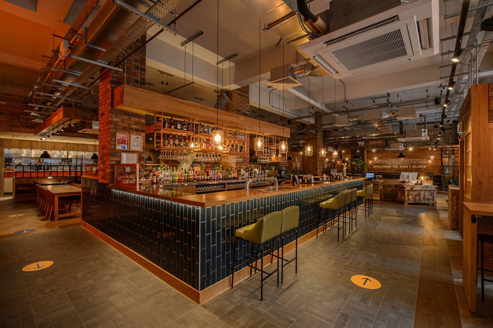 Orangey coloured industrial looking room with large central tiled bar