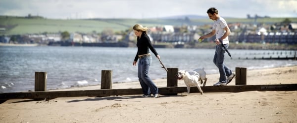 Lady and man walking a dog on Portobello Beach