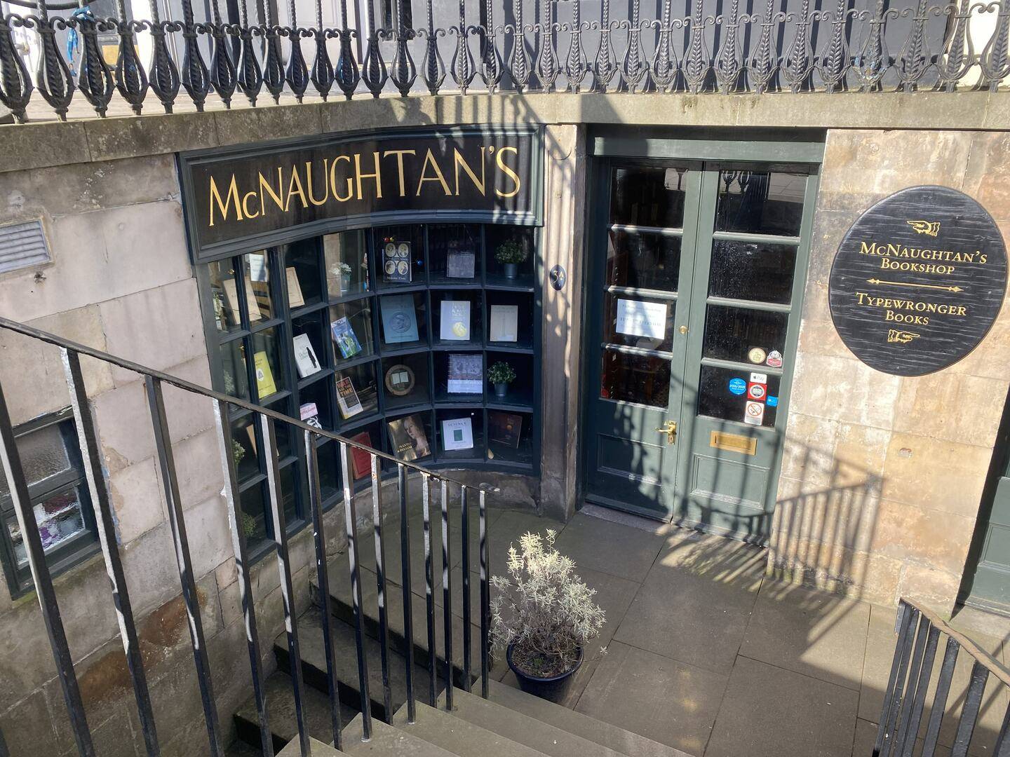 The window and door of a bookshop in the basement area of a tenement building.