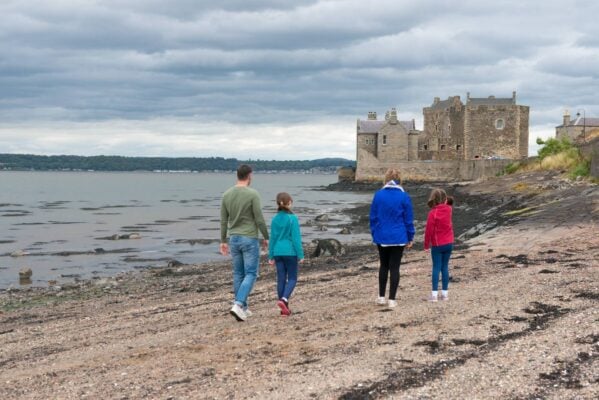 Family walking on beach towards a castle.