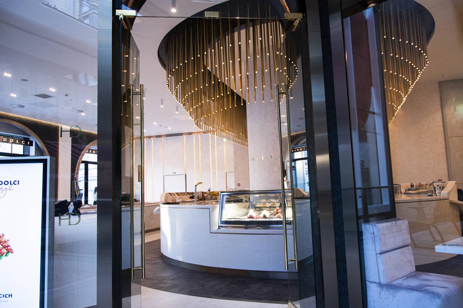 A view from the front door of the dessert counter and large gold light feature.,© Haute Dolci
