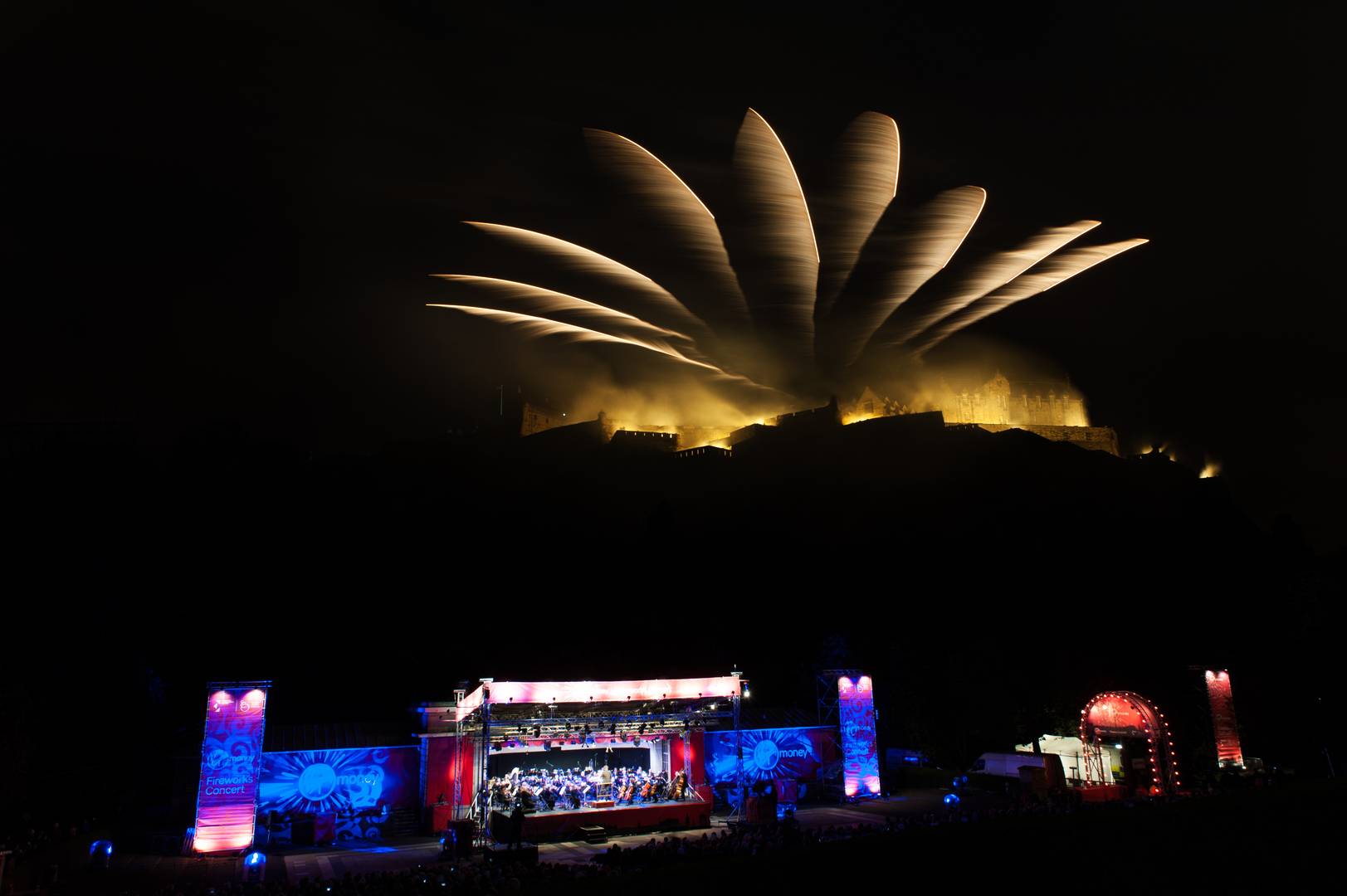 The Ross Bandstand at night during the Edinburgh Fireworks Concert with fireworks in the sky.