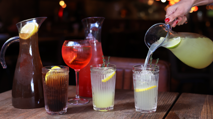 Pitchers of Long Island Ice Tea, Street Spritz and Hard Lemonade on table and being poured into tall tumbler glass