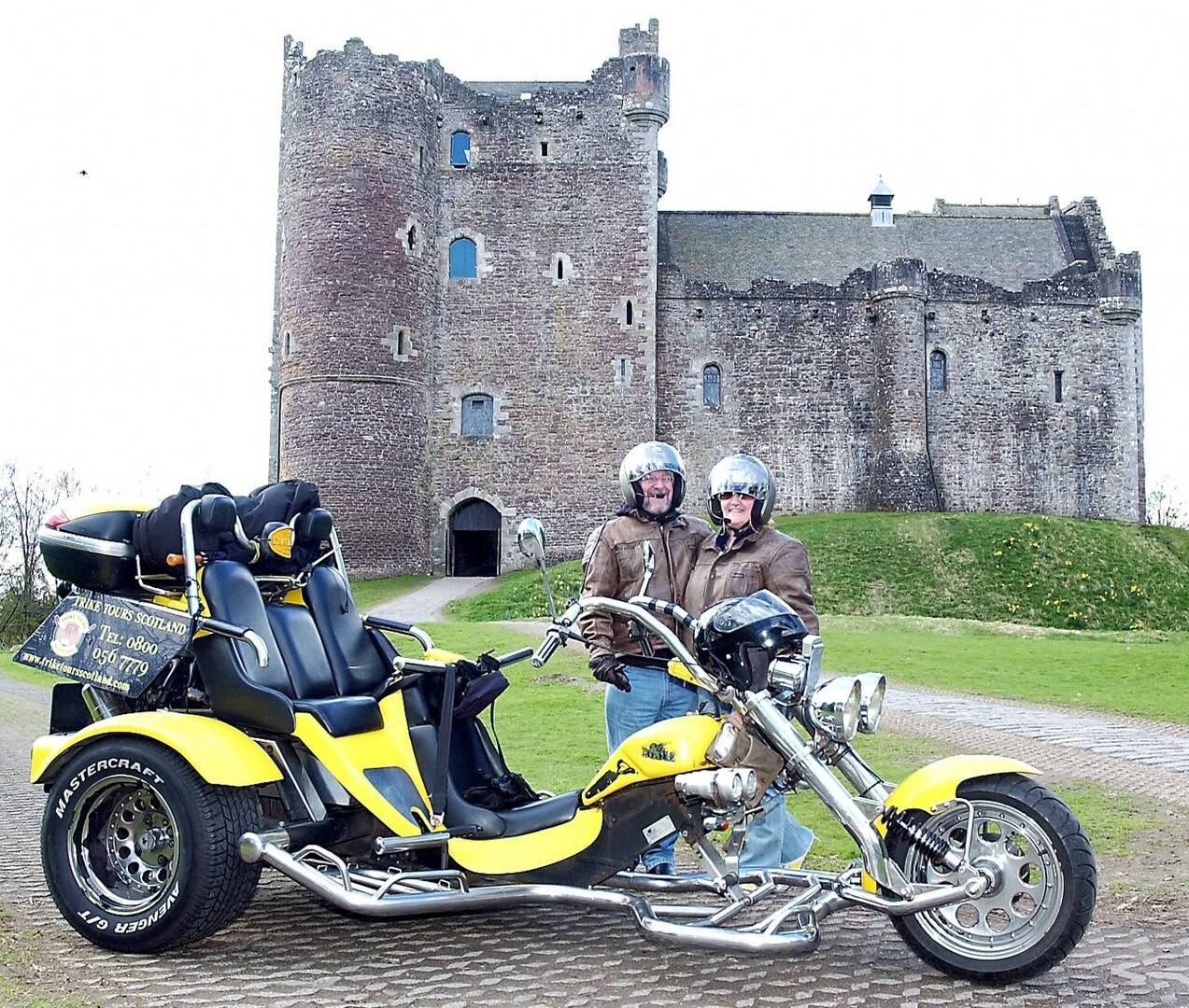 Couple standing with trike in front of a castle