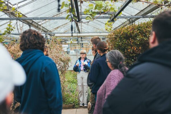 Woman giving a group of people a talk in greenhouse