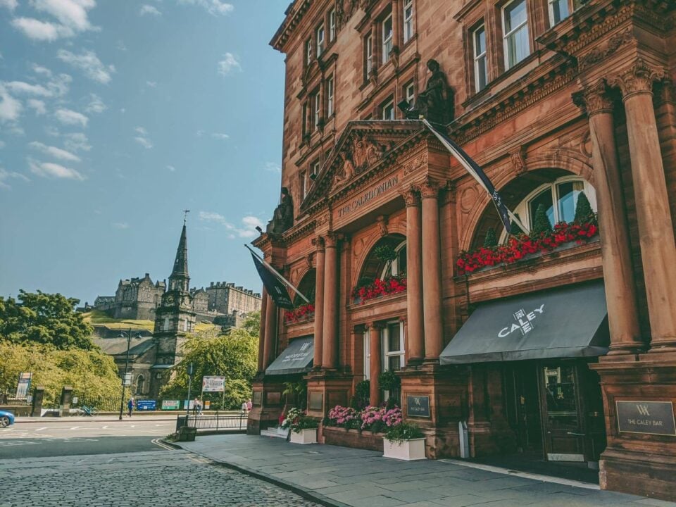 image of the red sandstone entrance to the hotel with church steeple and Edinburgh Castle in the background