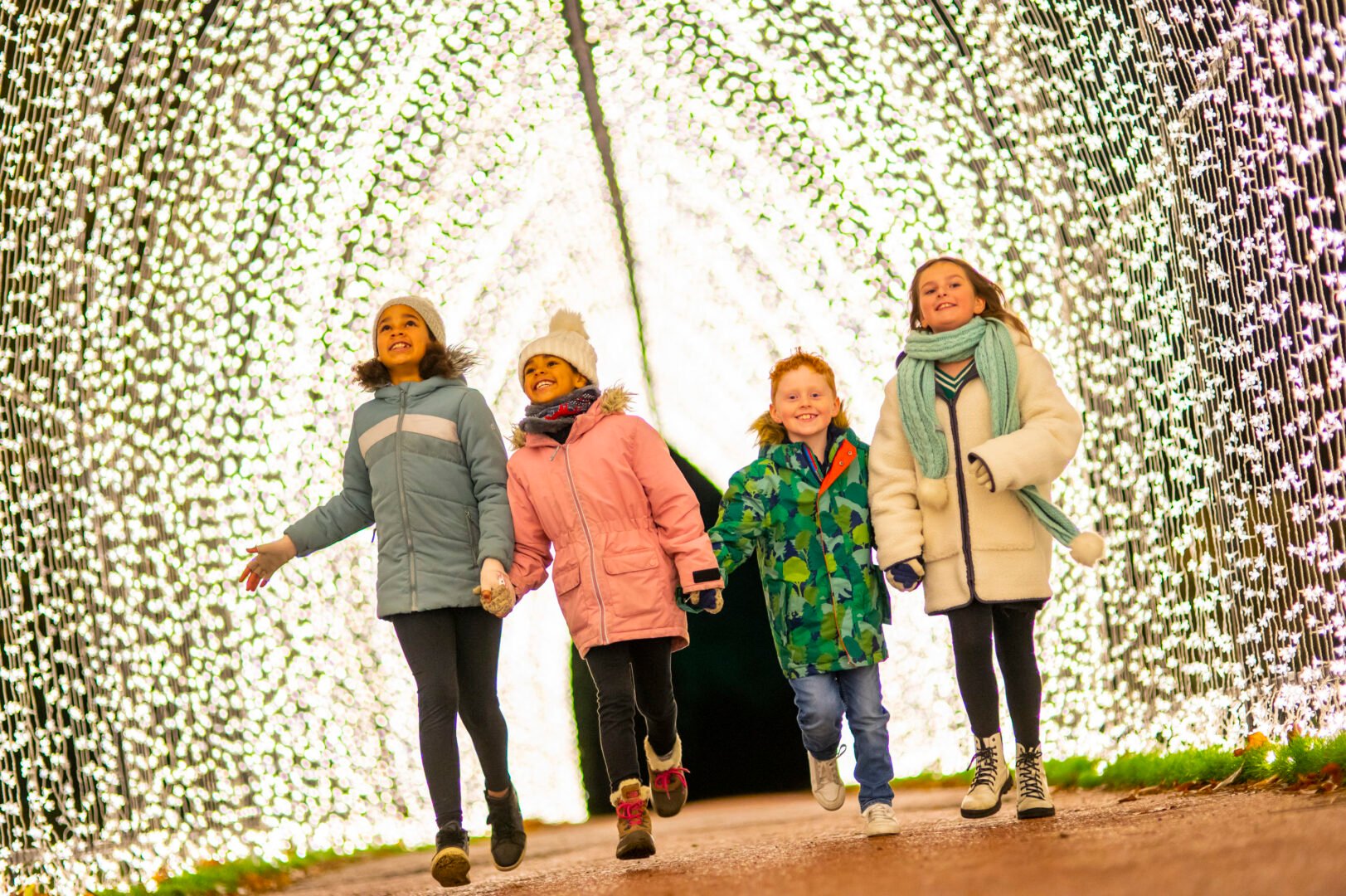 4 children walking through illuminated tunnel.