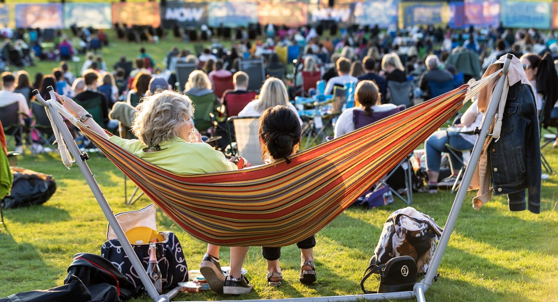 People sitting watching an outdoor screen with a film on.