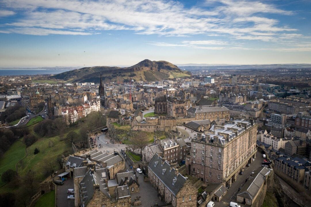 Sky view of a city and hills with a castle as the focal point.
