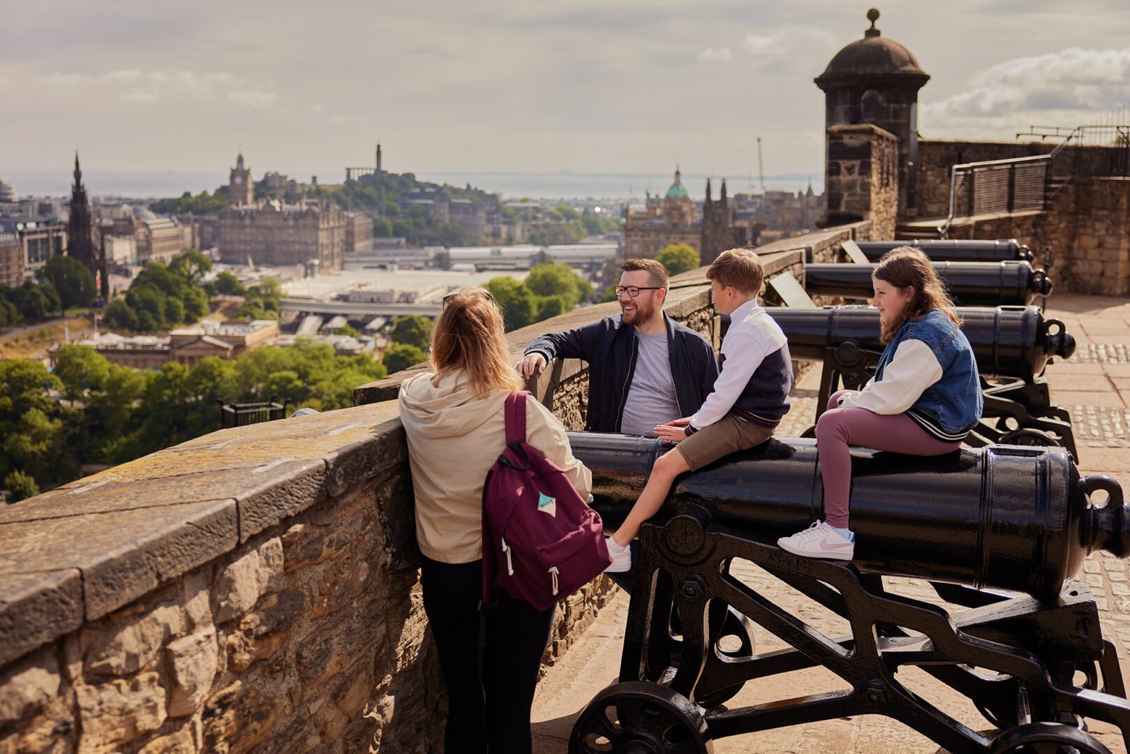 Family sitting on a canon looking at the Edinburgh skyline