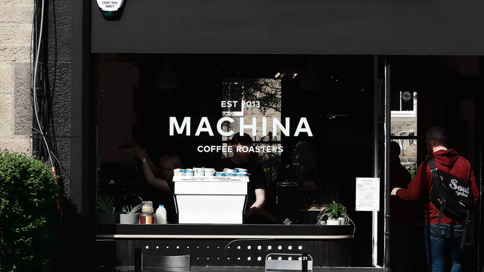 The shopfront for Machina Coffee. Black panelling with the company logo on the window in white., Machina Coffee