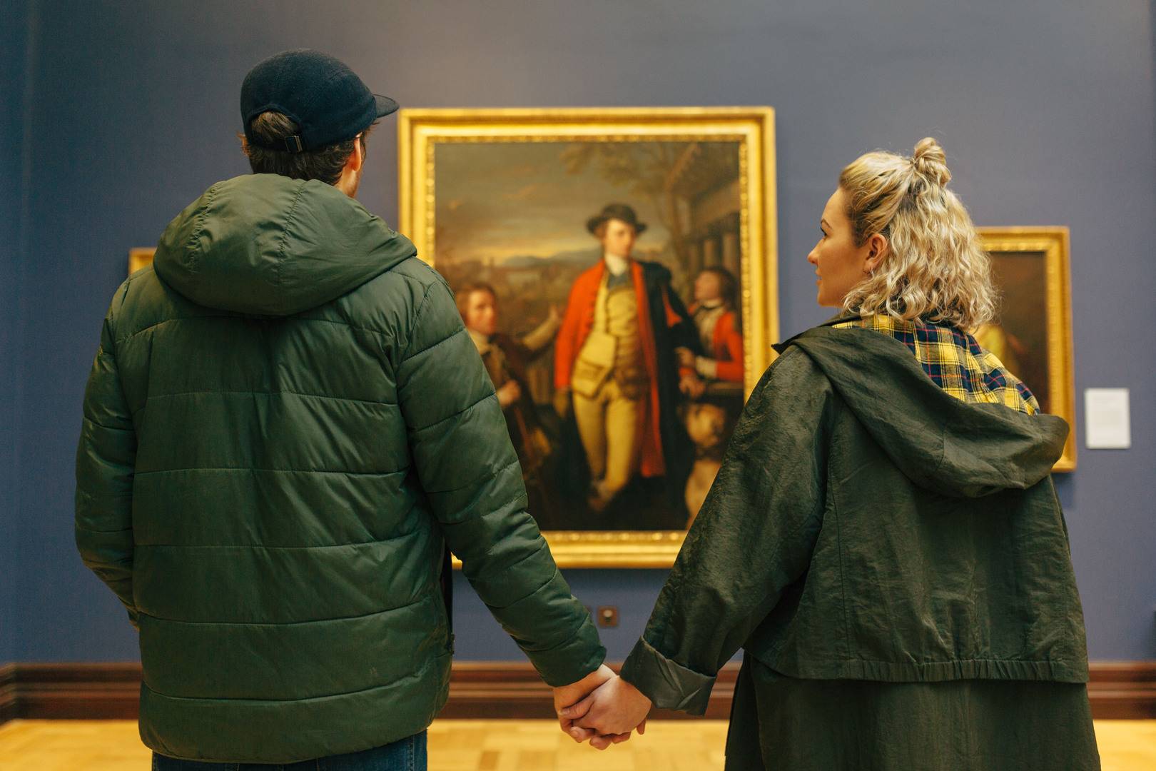 A couple hold hands in front of an historic painting, National Galleries of Scotland