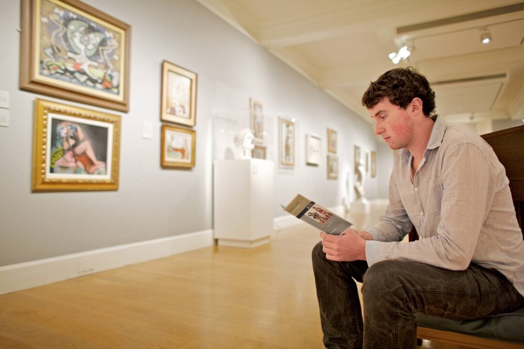 A man reads a leaflet while sitting in a gallery, National Galleries Scotland
