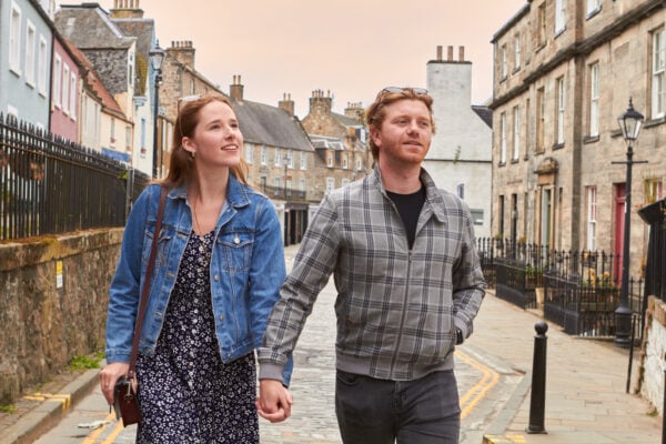 Couple walking hand in hand along South Queensferry High Street