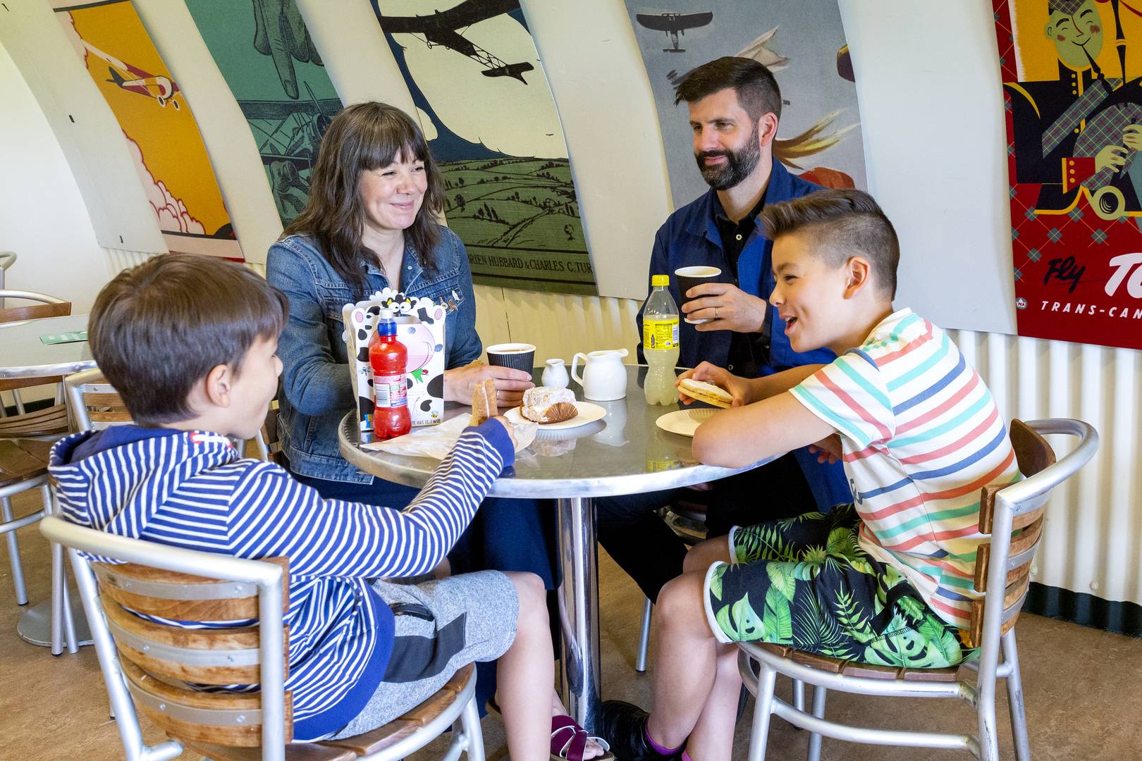A family of two adults and two children sit at a table in the cafe at the National Museum of Flight , Image © Ruth Armstrong Photography