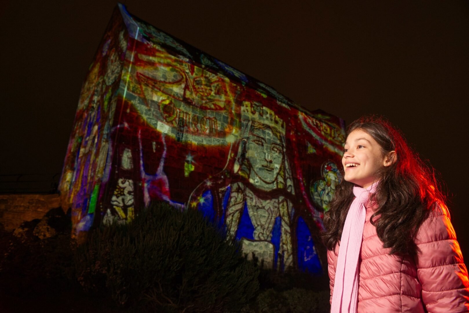 a girl looking at light projections on Edinburgh Castle during the Castle of Light display.