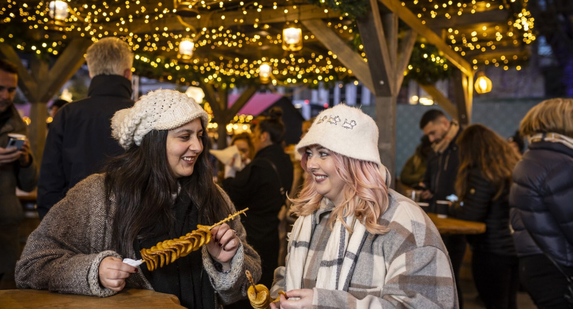 Two ladies enjoying festive food inside a festive cabin at Edinburgh Christmas Market