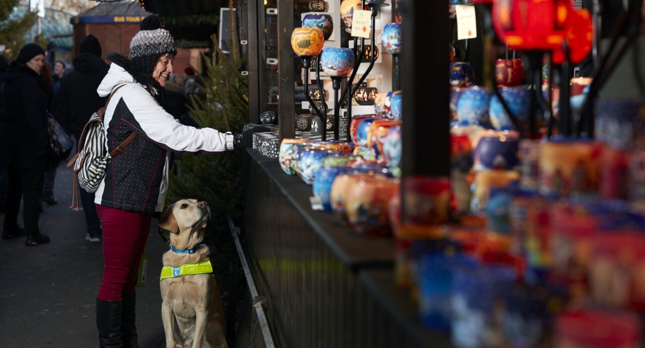 Edinburgh Christmas Market, lady at market stall with her assistant dog sitting.