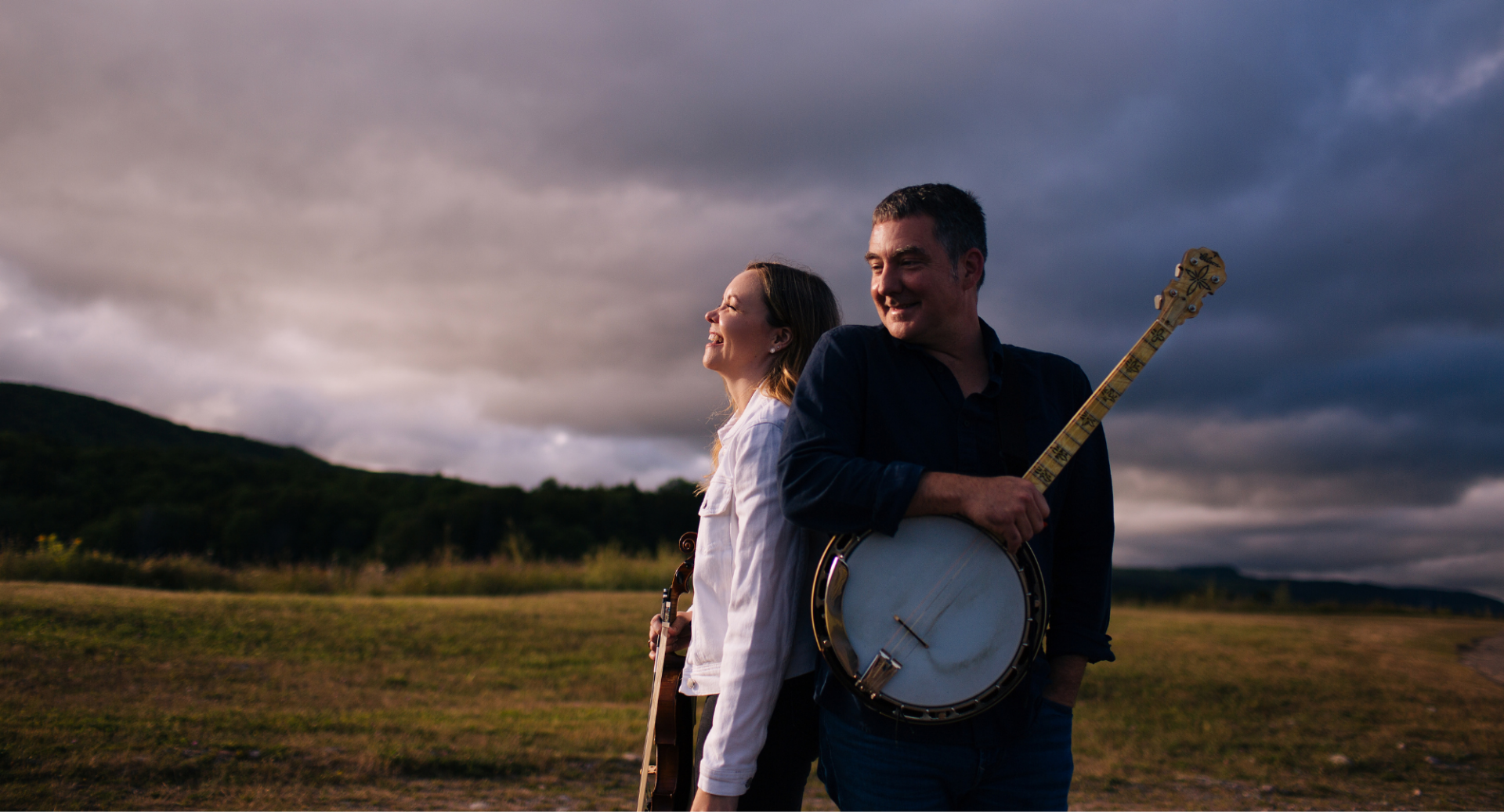 A man and woman standing in the Highlands, the man is holding a banjo