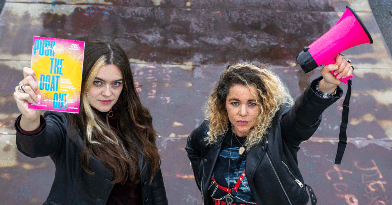 Two women holding a megaphone and poster