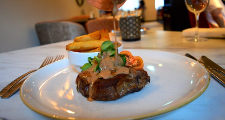 Ribeye steak with sauce being poured over top