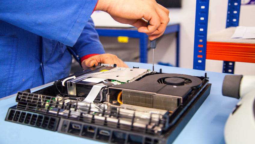 Man holding screwdriver and repairing games console