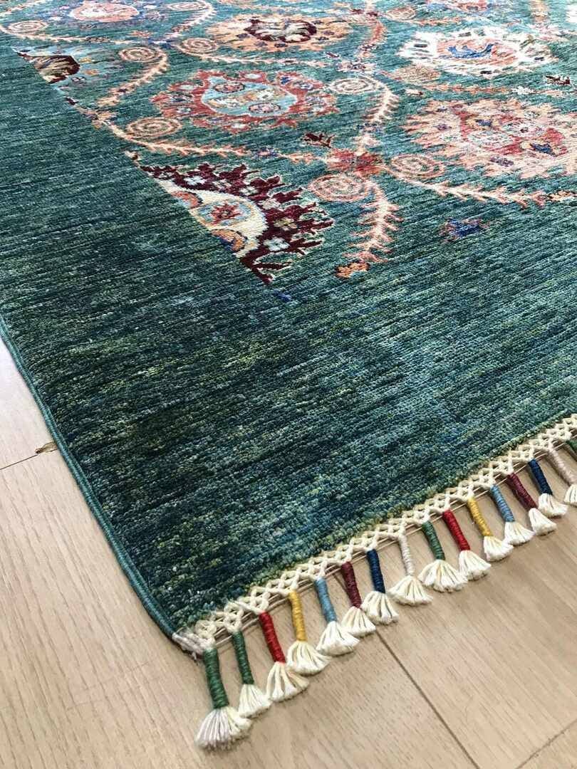 Corner of turquoise and rainbow tassel rug