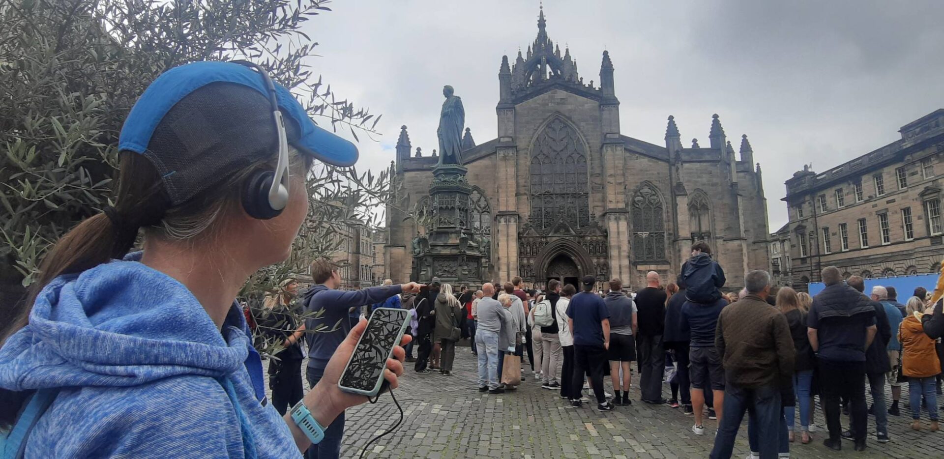 Woman listening to audio tour standing in front of St Giles' Cathedral
