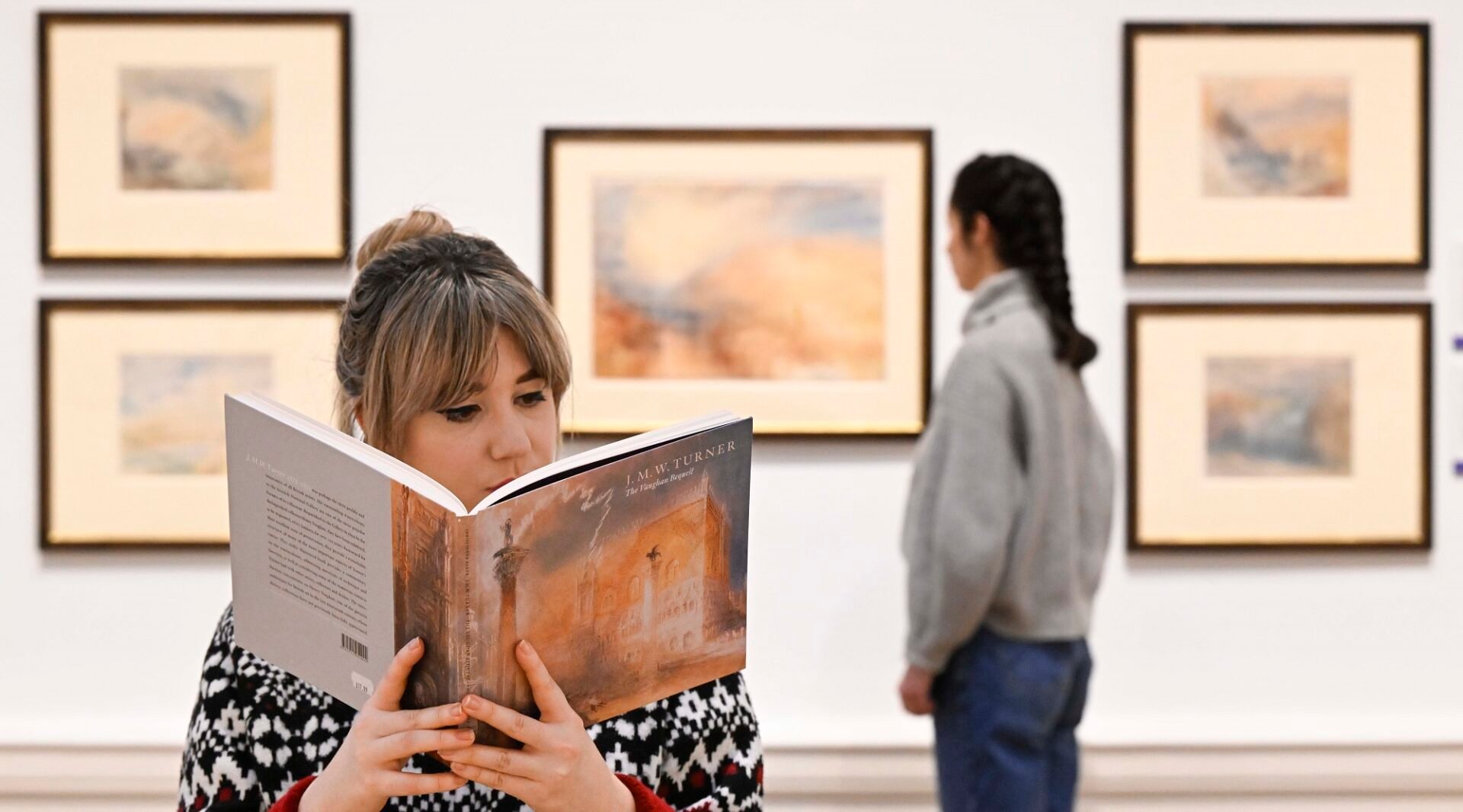 Lady looking at Turner images and Lady reading Turner Guide book at the Turner in January exhibition.