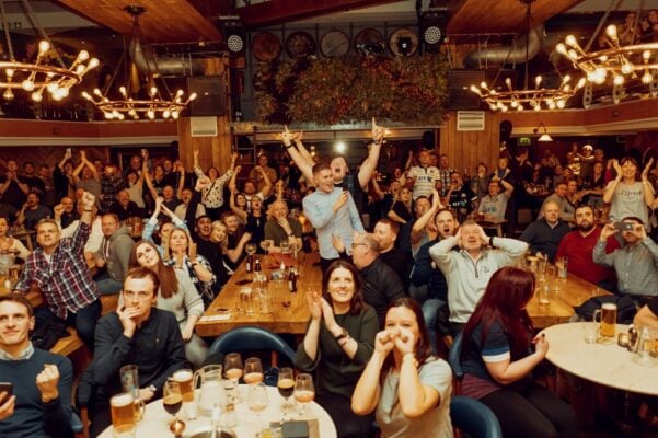 Room of people cheering happily at rugby dining at Brewhemia