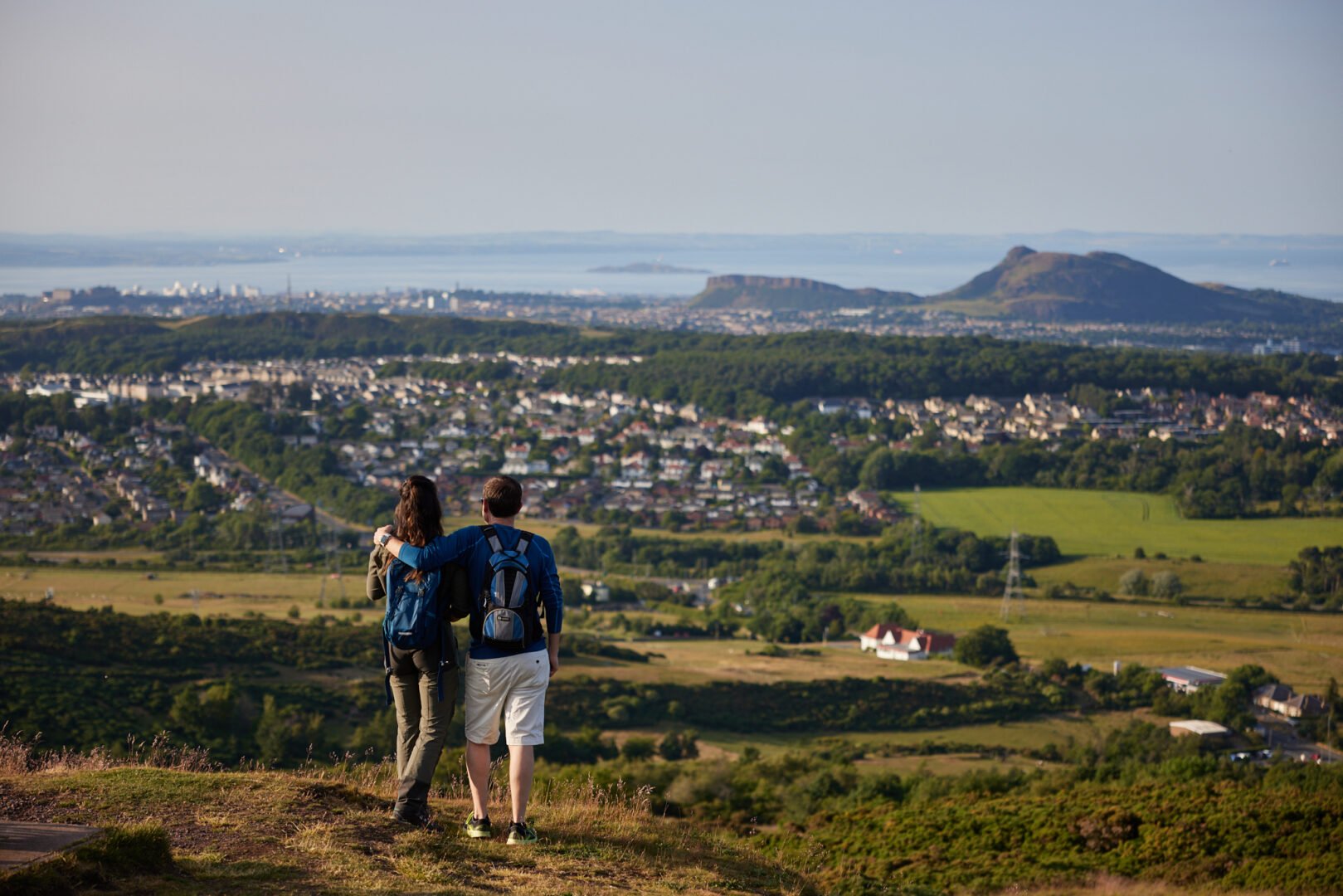 Couple walking in the Pentland Hills with City of Edinburgh as a backdrop