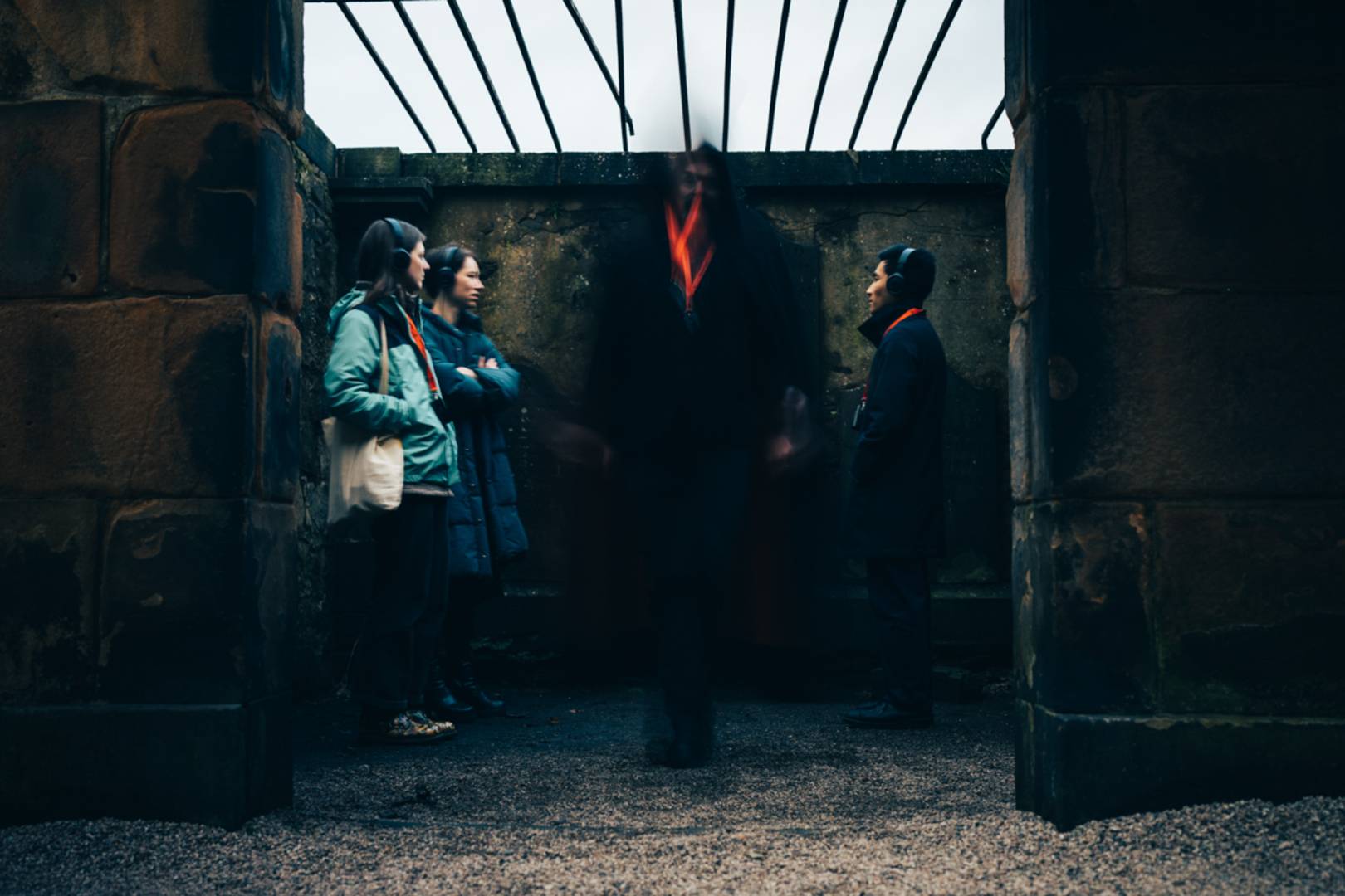 A ghostly figure surrounded by a tour group inside a kirkyard mausoleum.