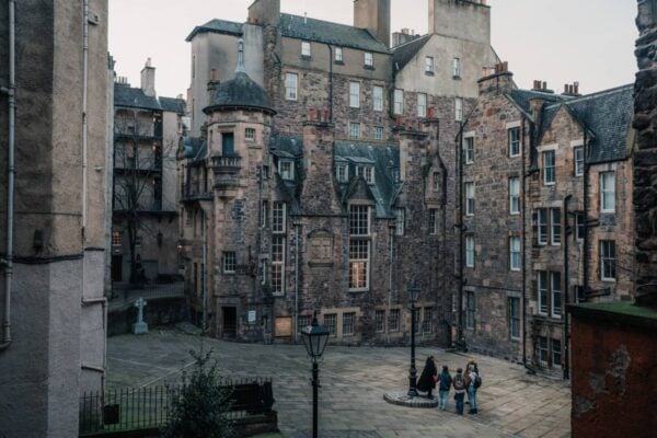 A tour group stands by a lamp in the middle of an empty courtyard off Edinburgh's Royal Mile.