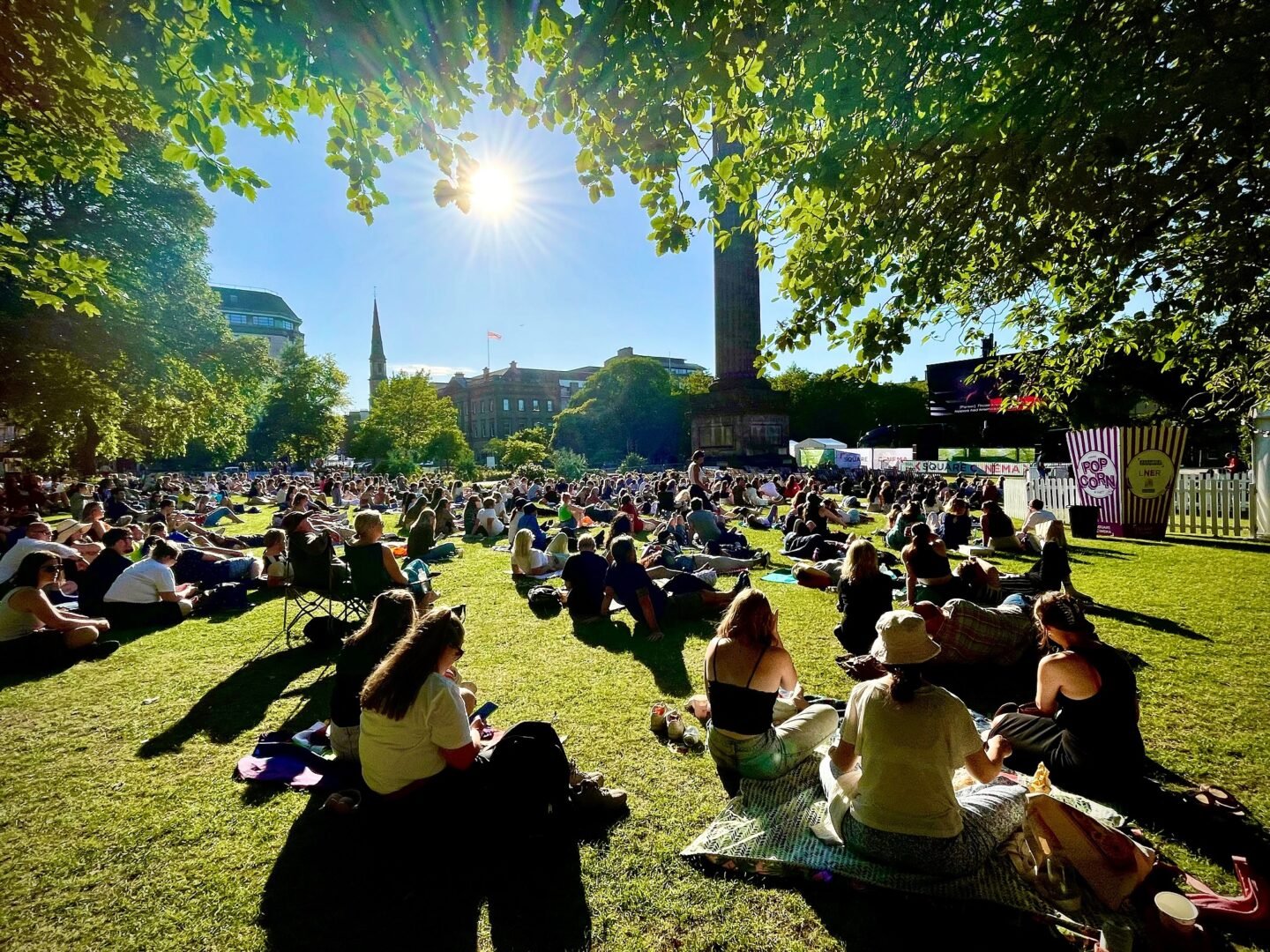 People sitting in the sun at St Andrews Square watching a film during the Square Cinema event