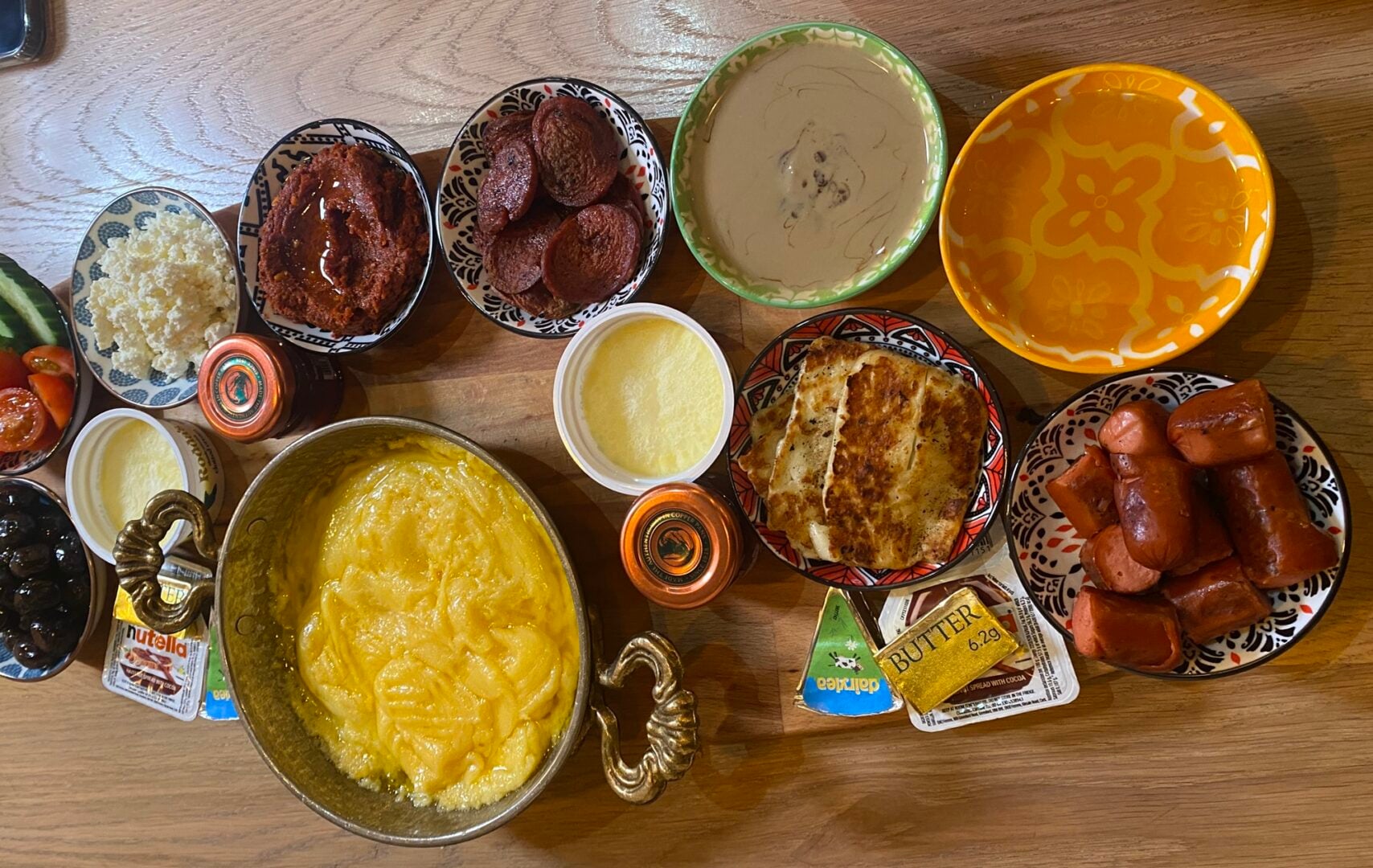Flatbread Turkish Breakfast made up of dips, meats, olives, salad, and cheese fondu.