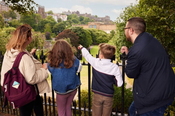 Family overlooking Princes Street Gardens with Edinburgh Castle in teh background