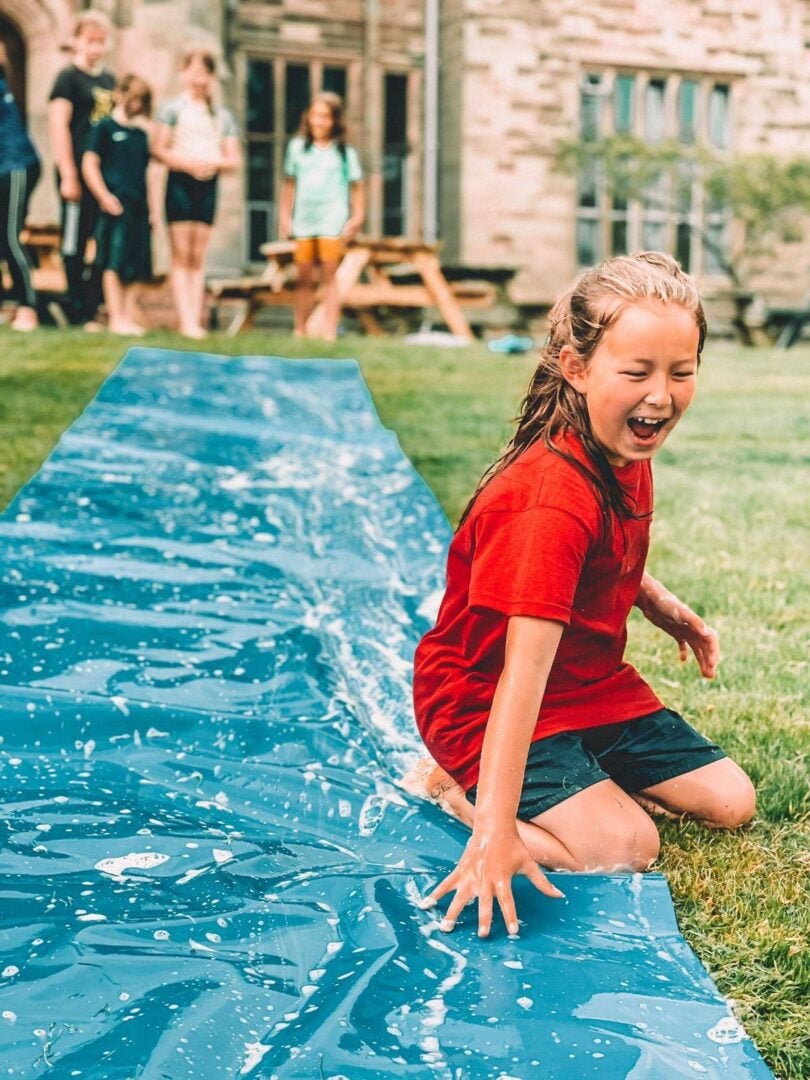 Picture of girl at previous summer camp on a slip and slide water slide. ,© The Wild Outdoors