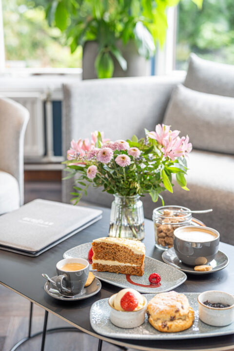 Cake and coffee on a table with a bunch of fresh flowers.