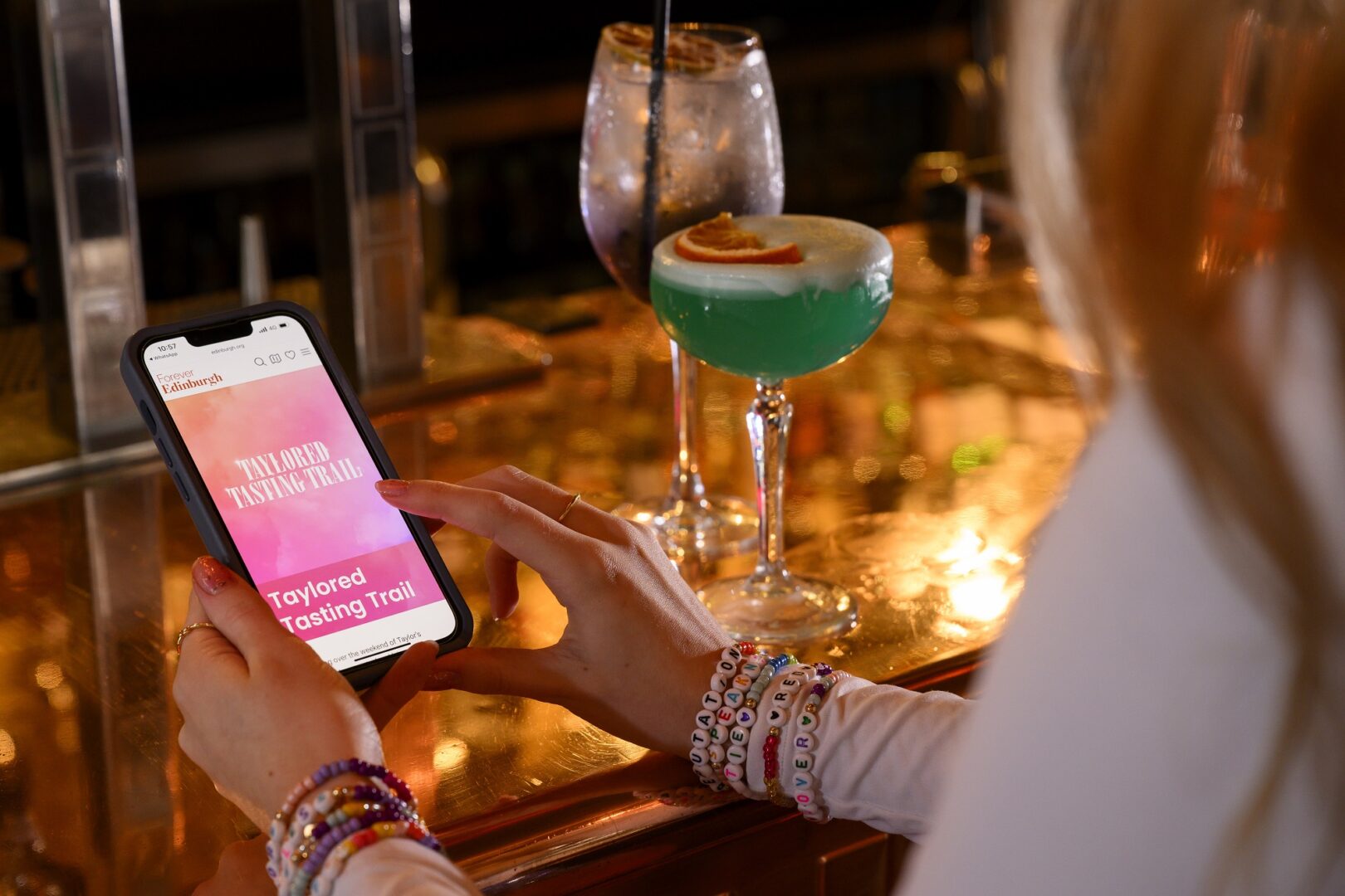 Taylor Swift Fan with a cocktail looking at the Taylor Swift Taste Trail on her mobile phone