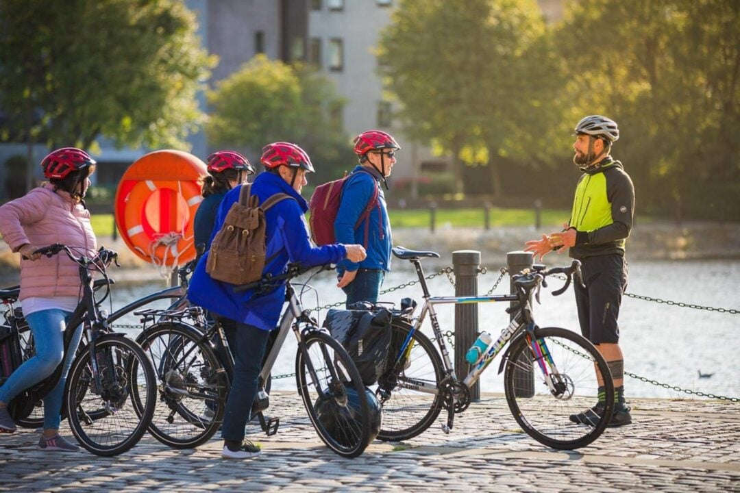 The guide of a bike tour of Edinburgh is telling a group of guests a story, in Leith. ,© Ricky's Bicycle Tours