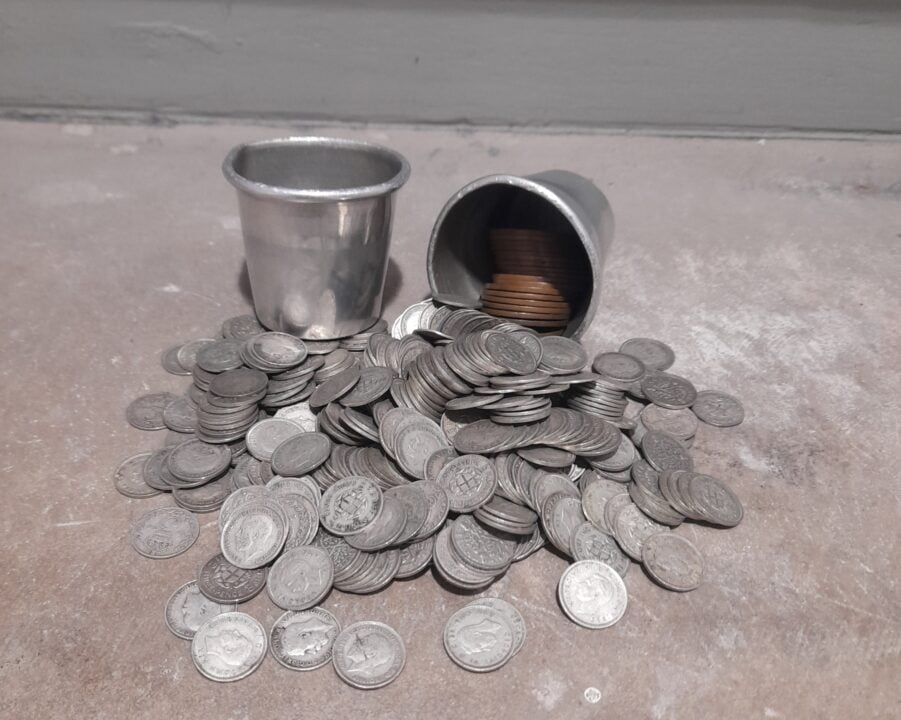 Silver coins pouring out of a tipped up silver cup