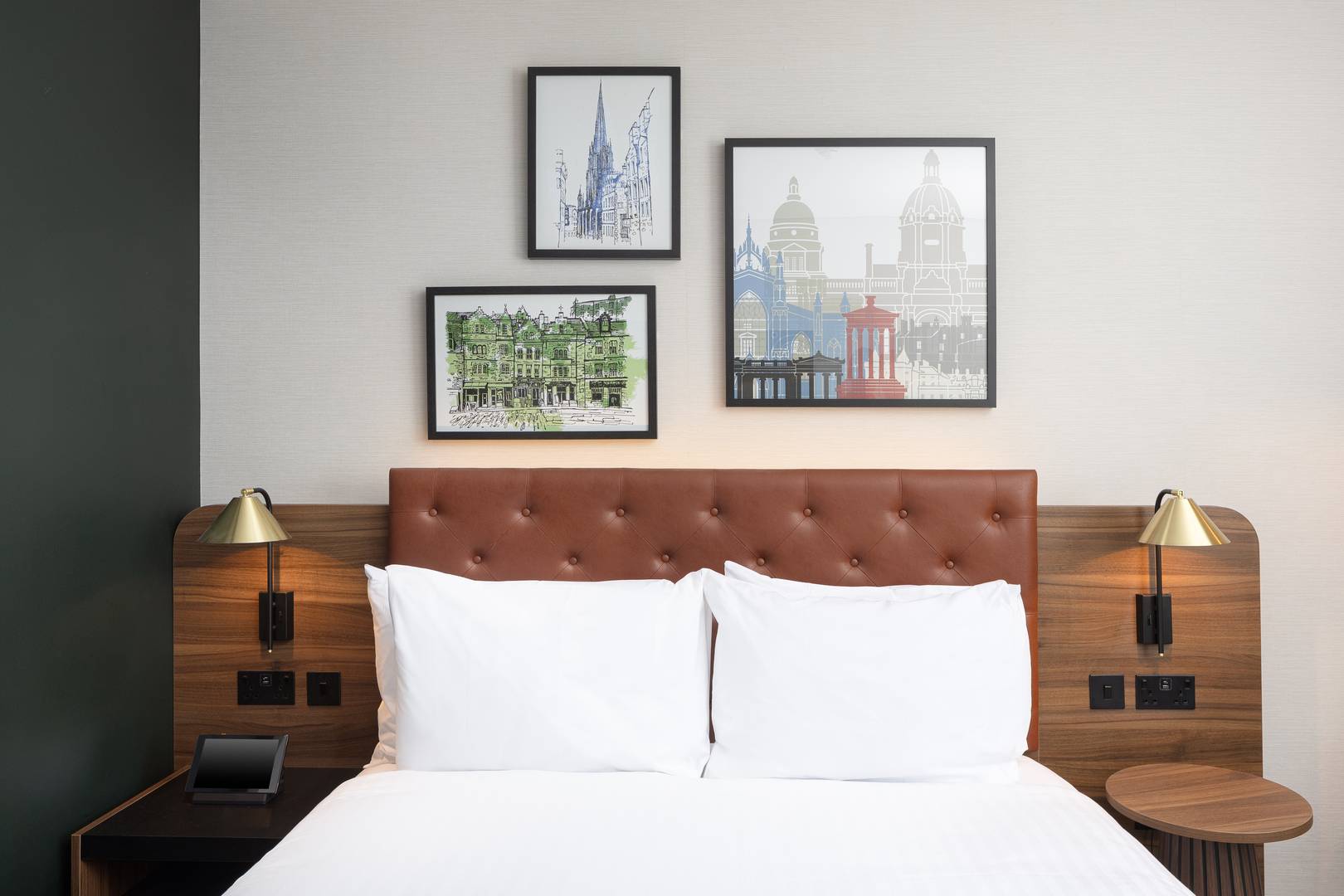 Large bed with leather headboard and pictures of the city above