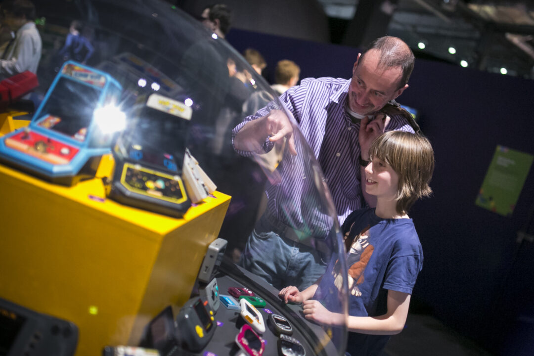 Dad and Son looking at display of hand held games at the Game On exhibition in Newcastle