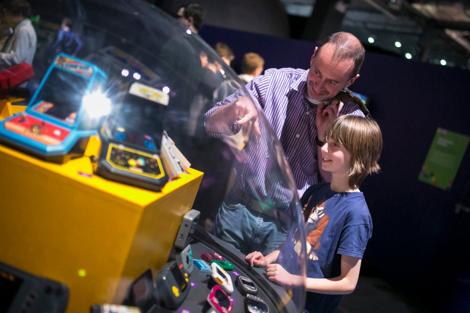 Dad and Son looking at display of hand held games at the Game On exhibition in Newcastle