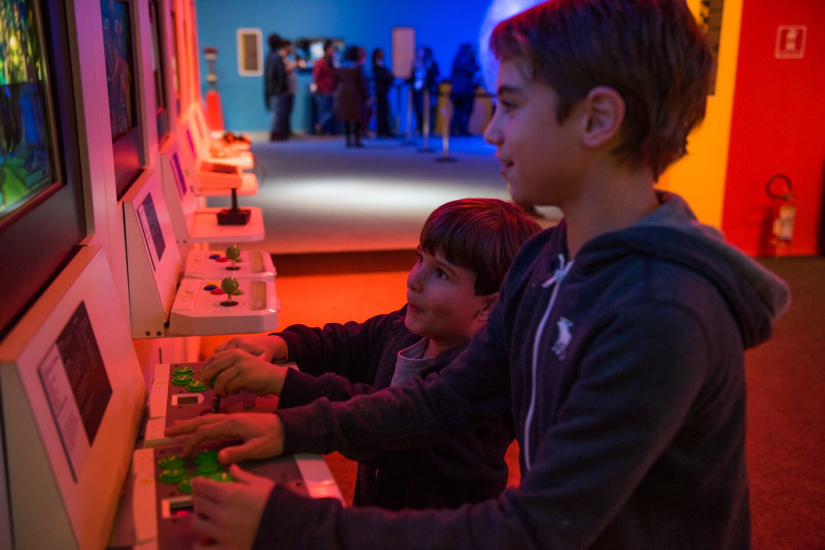 2 boys playing on an arcade machine at the Game On exhibition in Bienal de Sao Paulo