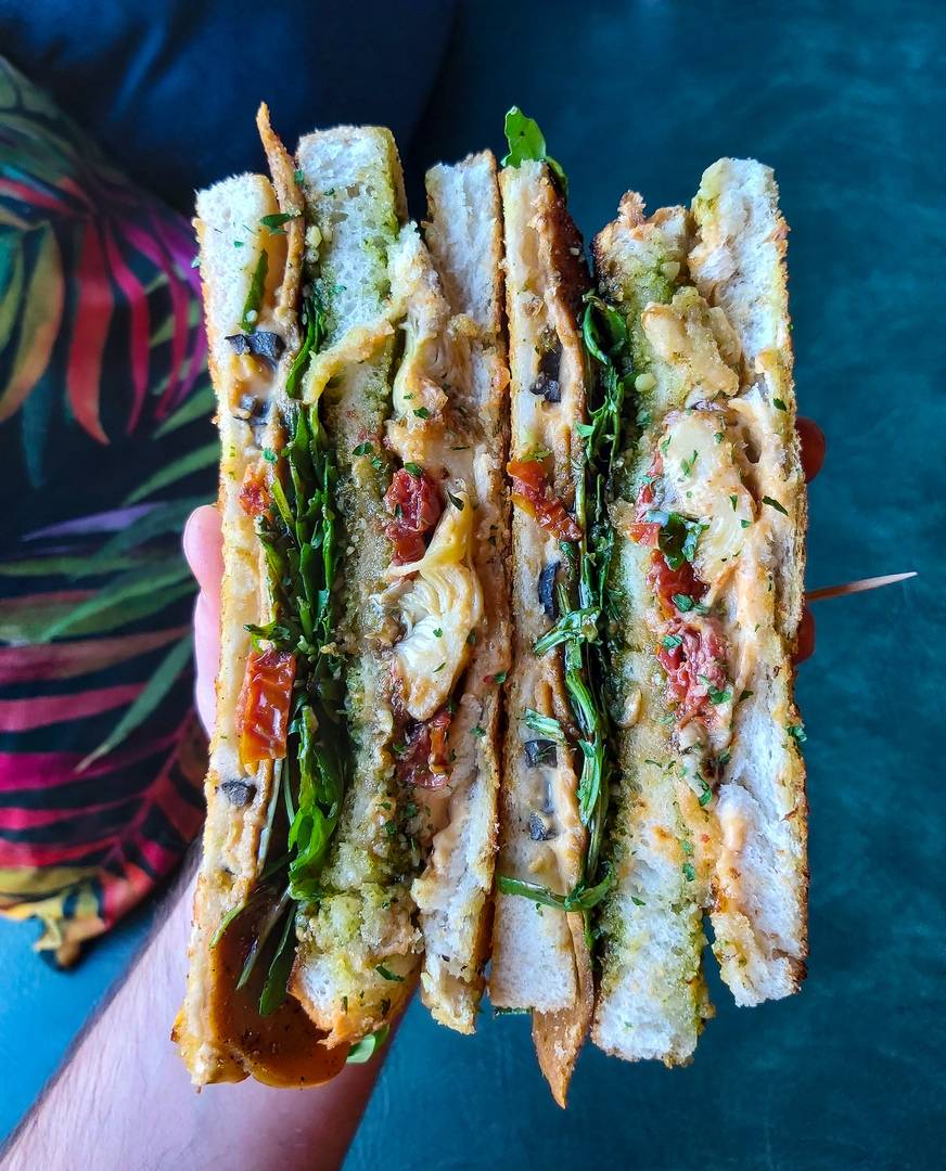 Club Med Sandwich - Three tiers of Mediterranean flavour. Cheeze, black olives, pesto toast, artichokes, sun-dried tomatoes, wild rocket and balsamic glaze